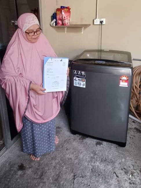 Pelanggan memegang borang penerimaan di sebelah mesin basuh Khind