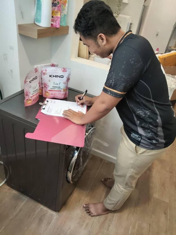 Pelanggan menandatangani borang penerimaan di atas mesin basuh