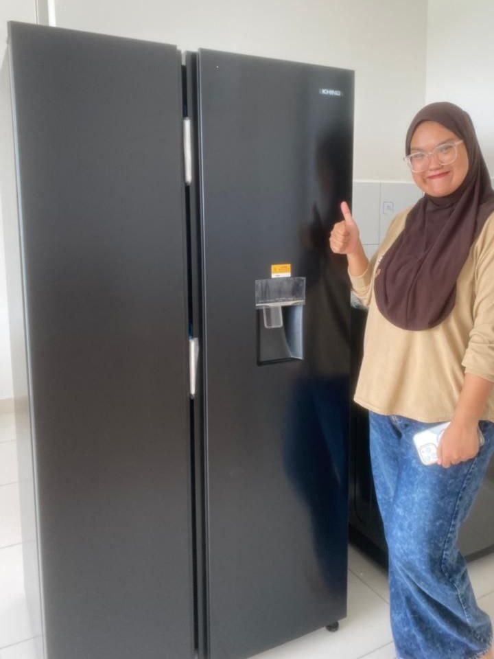 Pelanggan tersenyum memberi isyarat bagus di sebelah peti sejuk side-by-side