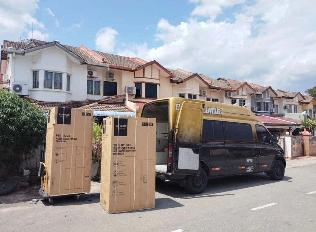 Van penghantaran menurunkan dua kotak peti sejuk Khind di hadapan rumah pelanggan
