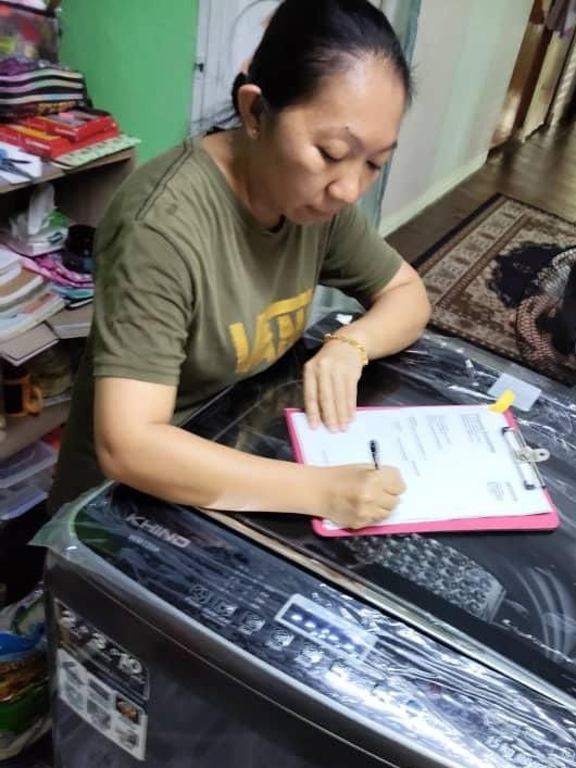 Pelanggan menandatangani borang penerimaan di atas mesin basuh Khind