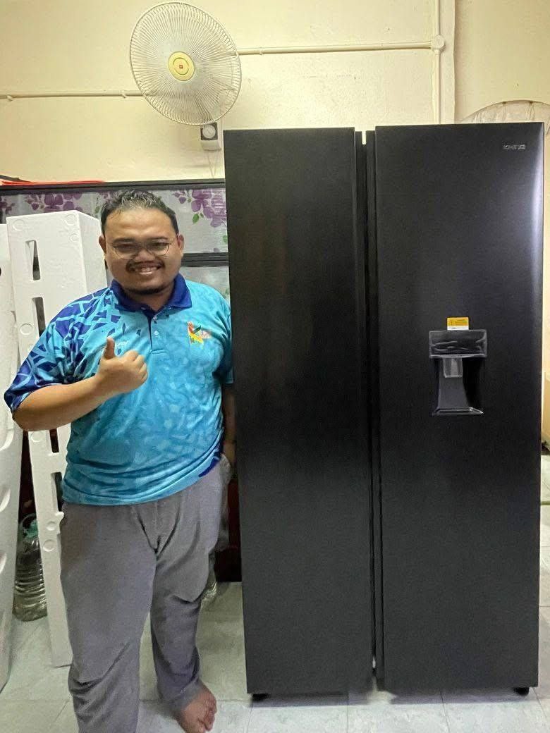Pelanggan tersenyum memberi isyarat bagus di sebelah peti sejuk side-by-side