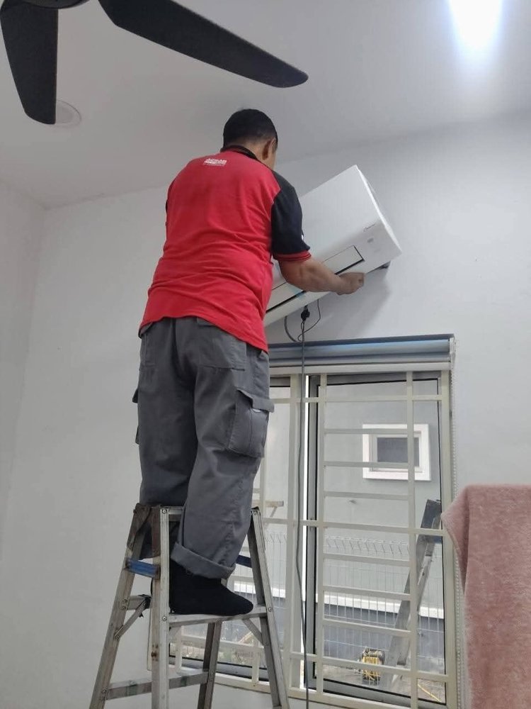 Juruteknik memasang unit dalaman aircond di bilik